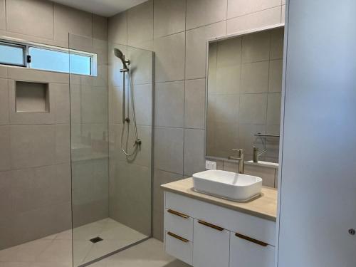 a bathroom with a shower and a sink and a mirror at 6 Yeri Drive - Rainbow Shores. Aircon. Pets Welcome. Walk to beach in Rainbow Beach