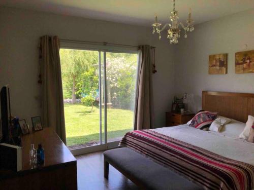 ein Schlafzimmer mit einem Bett und einer Glasschiebetür in der Unterkunft Excelente casa en Barrio Privado Los Arces in Pilar