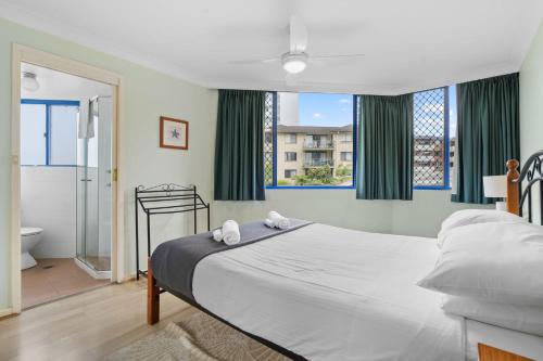 a bedroom with a large bed and a bathroom at Heritage 102 in Tuncurry
