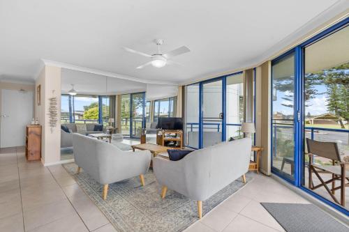 a living room with chairs and a table and windows at Heritage 102 in Tuncurry