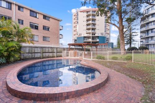 a small swimming pool in a brick yard with buildings at Heritage 102 in Tuncurry