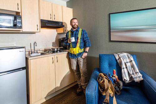 a man is standing in a kitchen with a coffee cup at Accent Inns Vancouver Airport in Richmond