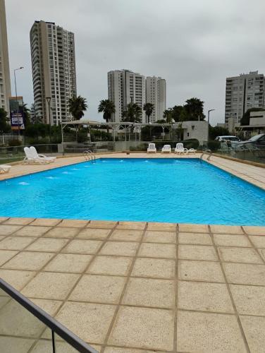 a large blue swimming pool with chairs and buildings at Marina 1 piso 23 in Coquimbo