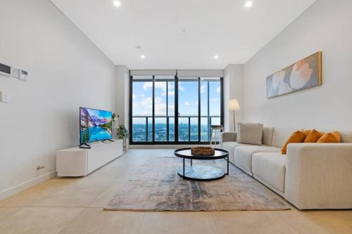 a living room with a couch and a table at Modern 2BR with City Views & Pool Near Parramatta in Sydney