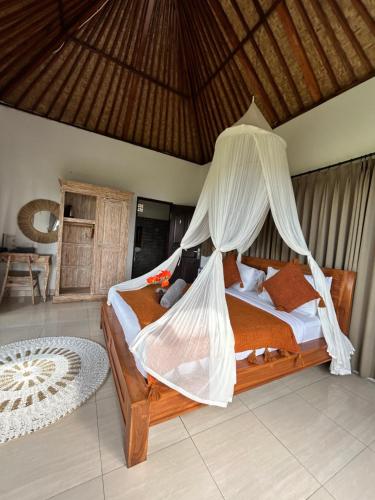a bedroom with a bed with a mosquito net at Batur cottage in Kubupenlokan