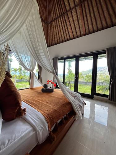 a bedroom with a bed with a canopy and large windows at Batur cottage in Kubupenlokan