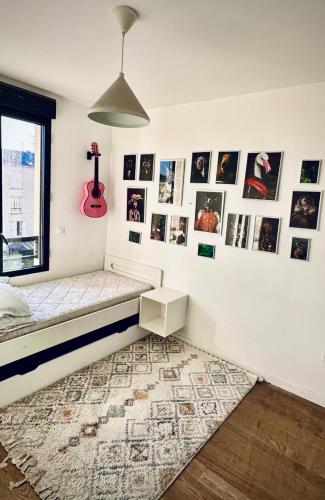 Cette chambre comprend un lit et des photos sur le mur. dans l'établissement La Colombe, à Colombes