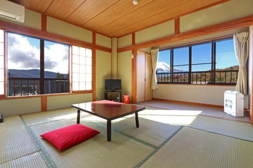a living room with a table and large windows at 山中湖ハイツ in Yamanakako