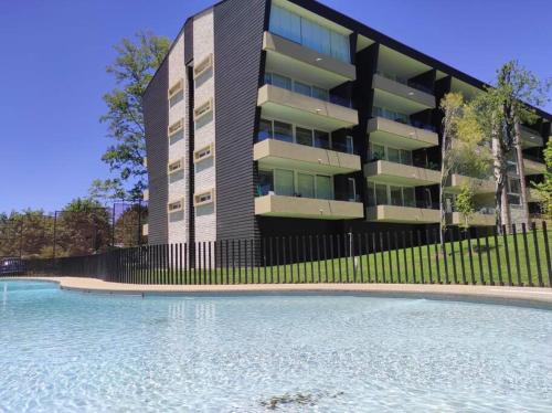 a building with a swimming pool in front of a building at Alta Vista Pucon Centro II in Pucón
