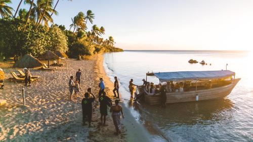 a group of people standing on a boat on the beach at Likuri Island Resort Fiji in Natadola
