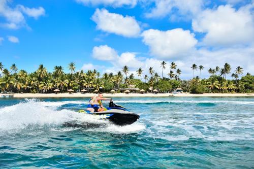 a man and a dog riding a jet ski in the ocean at Likuri Island Resort Fiji in Natadola