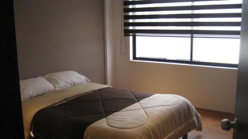 1 dormitorio con 1 cama frente a una ventana en Vacacional Quito, en Quito