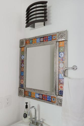 a bathroom mirror with a mosaic border on a wall at Casa Fenix in Sayulita