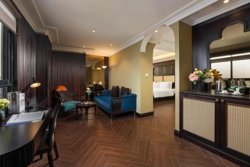 a hotel room with a blue couch and a bedroom at MAY DE VILLE Crown Hotel in Hanoi
