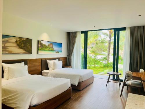 a hotel room with two beds and a window at The Vista Beach Resort Phan Thiết in Phan Thiet