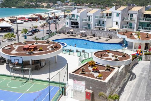 an aerial view of a pool at a resort at Condomínio Club a 50m PRAIA dos Anjos - Unidades com 2 QUARTOS, PISCINA, estacionamento e portaria 24h - Área de lazer 3000m, wi-fi 800MB, churrasqueira e cozinha completa in Arraial do Cabo