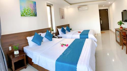a bedroom with two beds with blue and white pillows at EasyLife Villa Hoi An in Tân Thành (1)