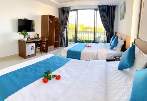 a hotel room with two beds and a television at EasyLife Villa Hoi An in Tân Thành (1)