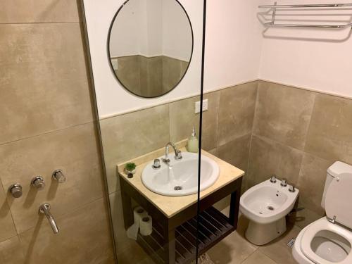a bathroom with a sink and a toilet and a mirror at Allende Apart St in Villa Allende