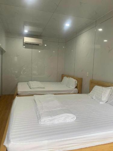 a bedroom with two beds with white sheets at Huy Hoàng Homestay Kiên Giang in Lai Sơn