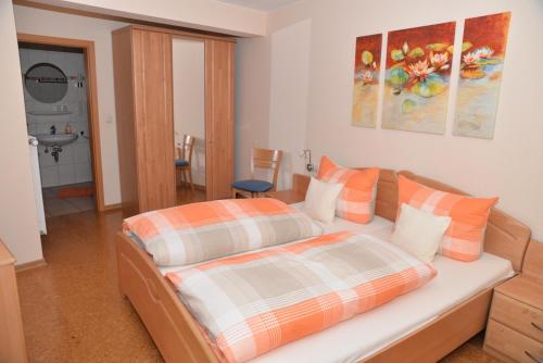 Schlafzimmer mit einem Bett mit orangefarbenen und weißen Kissen in der Unterkunft Pension Basten in Ellenz-Poltersdorf