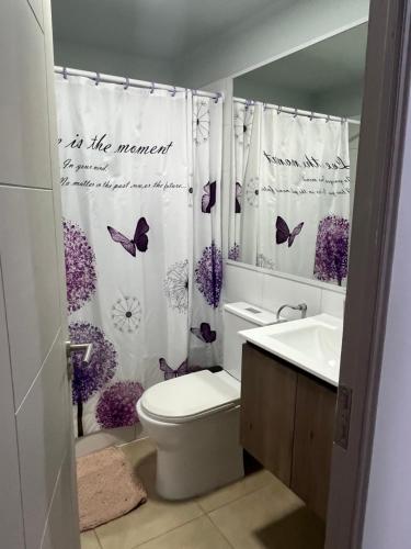 a bathroom with a toilet and a shower curtain with butterflies at Depto Montserrath en Condominio 3D 1B Parking Excelente Conectividad, Atención Empresas-Facturas in Chillán