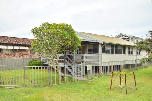 a house with a fence in front of a yard at Sunshine Cottage - Bring your own linen. in South West Rocks