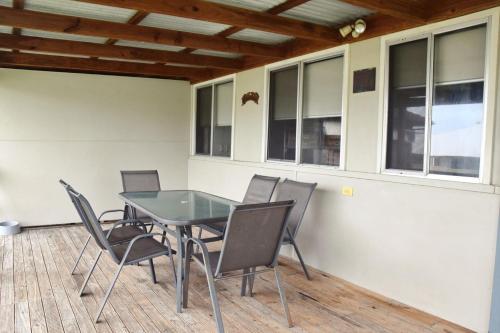 a dining room with a glass table and chairs at Sunshine Cottage - Bring your own linen. in South West Rocks