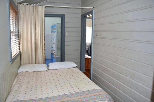 a small bedroom with two beds in it at Sunshine Cottage - Bring your own linen. in South West Rocks