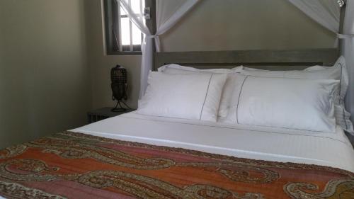 Thalpe Bungalows في يوناواتونا: غرفة نوم بسرير ذو شراشف ووسائد بيضاء
