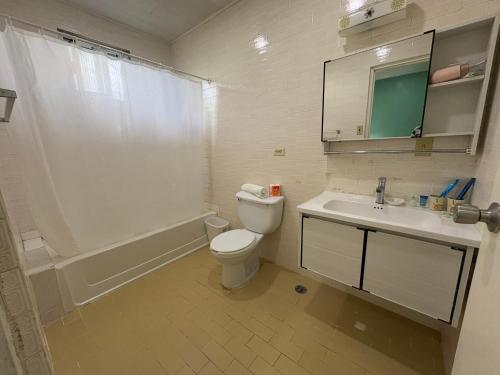 a bathroom with a toilet and a sink and a shower at Beach Garden Hotel in Saipan