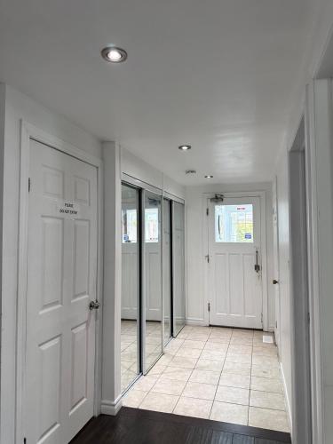 a hallway with white walls and doors and a tile floor at Riverwood Home in Mississauga