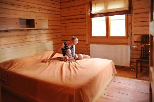 un niño sentado en la parte superior de una cama en Loma-Väkkärä Holiday Cabins Saimaa, en Liiansaari