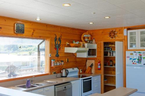 a kitchen with wooden walls and a white refrigerator at A Classic Kiwi Bach in South Bay in Kaikoura
