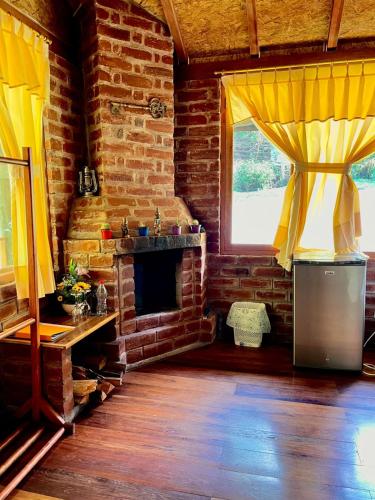 a living room with a brick fireplace and yellow curtains at Munay Wasi by Hospedaje Puntzán in Baños