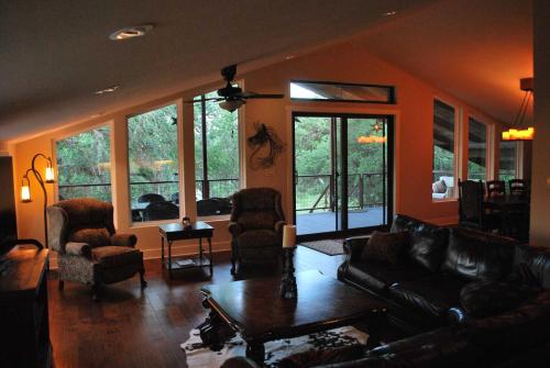 a living room with a couch and chairs and windows at Rockin' B Ranch Creek View Barndominium in Pipe Creek