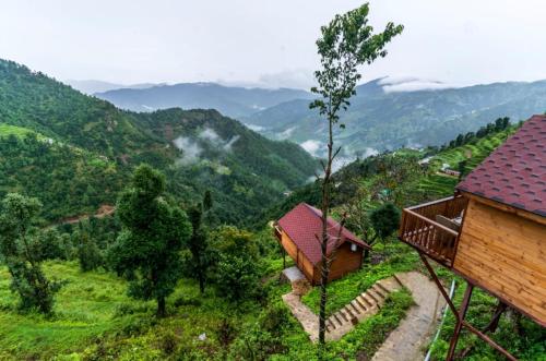 a house on a hill with mountains in the background at The Devan Wood Resort in Dhanaulti