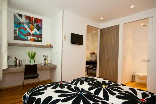 um quarto com uma cama, uma secretária e uma televisão em @Cocoon em Ypres