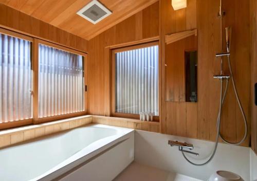 a bath tub in a bathroom with wooden walls and windows at NIPPONIA Sawara Merchant Town Hotel in Katori