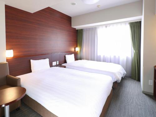 a hotel room with two beds and a window at Dormy Inn Himeji Natural Hot Spring in Himeji