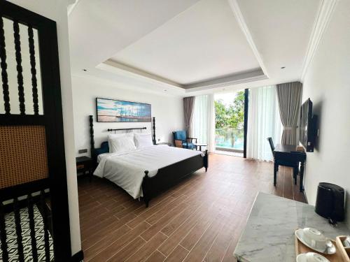 a hotel room with a bed and a desk and a window at The Vista Beach Resort Phan Thiết in Phan Thiet