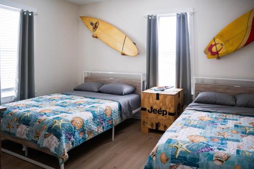 a bedroom with two beds and a surfboard on the wall at The Board House Longboard in Galveston