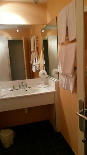 a bathroom with a sink and a mirror and towels at Hotel Le Saint Aubin in Gournay-en-Bray