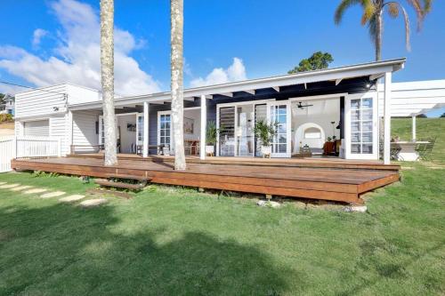 a house with a large deck with palm trees at Rosewood House in Lower Beechmont