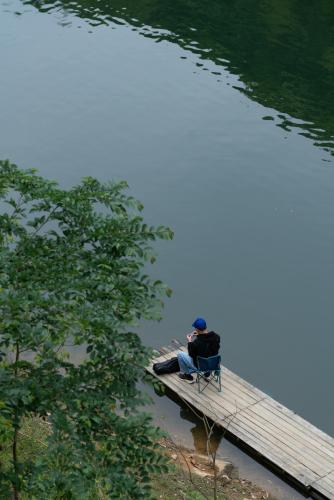 a person sitting on a bench on a dock next to a lake at Yakamoz Qianchuan Hotel in Lin'an