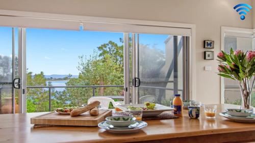 a dining room with a table and a large window at Penguins Rest in Culburra Beach