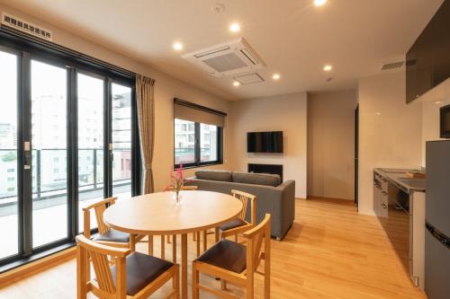 a kitchen and living room with a table and chairs at TEN APARTMENT HOTEL Hakata Reisen in Fukuoka