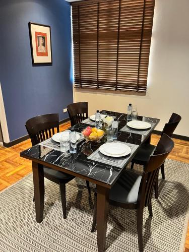 a black dining room table with chairs and plates and fruit on it at Asoke Residence Sukhumvit by UHG in Bangkok