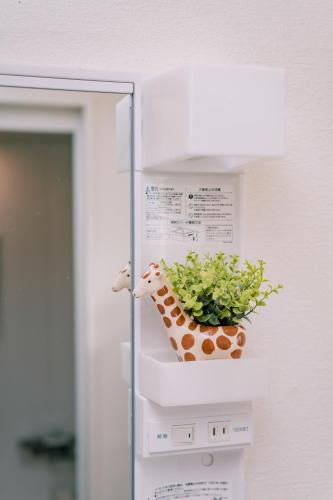 a stuffed giraffe on a shelf with a plant at Natsumi 2 ホテル in Tokyo
