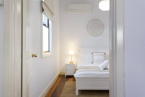 a white bedroom with a bed and a window at The Coastal Nest - South Fremantle in South Fremantle